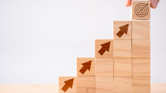 Hand putting Coins in glass jar with retro alarm clock